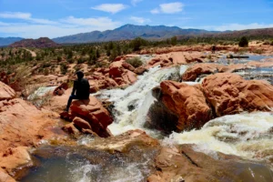 A scenic view of Gunlock State Park featuring a tranquil reservoir surrounded by red rock cliffs and desert landscapes.