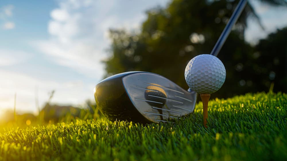 gold ball in grass with club