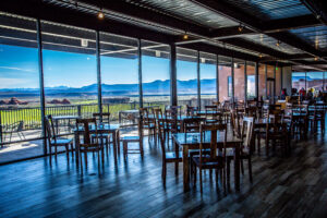An interior dining hall with wooden tables and floor-to-ceiling windows overlooking a desert golf course and mountains, illustrating the modern amenities of premier corporate retreat venues St. George Utah offers.