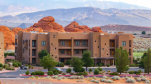 A multi-story southwest-style resort condo building surrounded by red rock formations and desert mountains, highlighting the spacious Sand Hollow Resort room types large group vacation rentals.